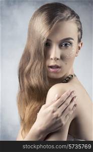 beauty portrait of pretty woman with braid hair-style, creative starry make-up and stylish necklace. Looking in camera, naked shoulders