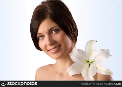 beauty portrait of pretty young woman with a big white lily on her shoulder