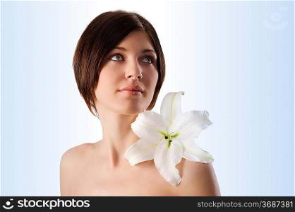 beauty portrait of pretty young woman with a big white lily on her shoulder