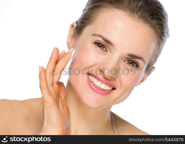 Beauty portrait of smiling young woman applying creme