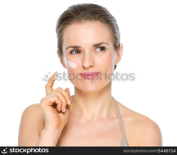 Beauty portrait of thoughtful young woman with creme on cheek