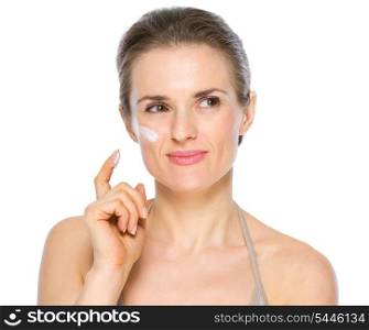 Beauty portrait of thoughtful young woman with creme on cheek