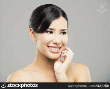 Beauty portrait of young asian woman with a beautiful smile, over a gray background