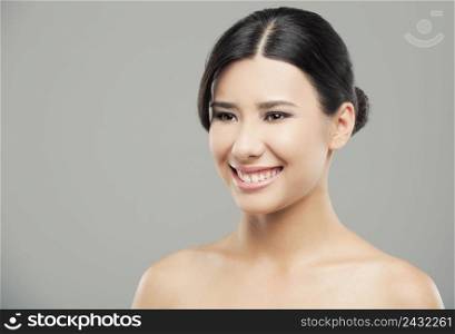 Beauty portrait of young asian woman with a beautiful smile, over a gray background