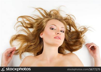 beauty portrait of young blond woman in black underwear with hair style laying down on white