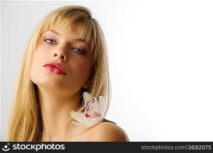 beauty portrait of young blond woman with orchid on her shoulder