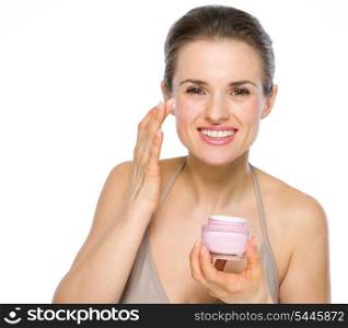 Beauty portrait of young woman applying creme