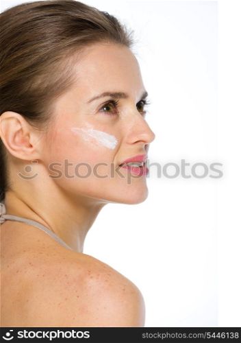 Beauty portrait of young woman with creme on cheek looking on copy space
