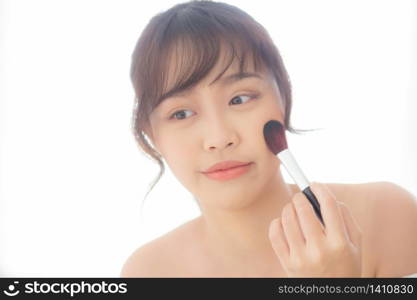 Beauty portrait young asian woman smile with face looking mirror applying makeup with brush cheek in the bedroom, beautiful of girl holding blusher, skin care and cosmetic concept.