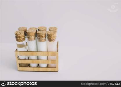beauty products test tubes wooden container white backdrop
