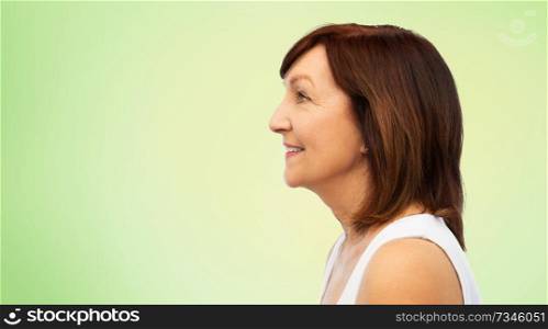 beauty, rhinoplasty and old people concept - profile of smiling senior woman over lime green natural background. profile of smiling senior woman over white