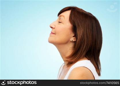 beauty, rhinoplasty and old people concept - profile of smiling senior woman over blue background. profile of smiling senior woman over blue