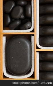 Beauty salon. Close up of black spa zen massage stones in wooden case as background. Relax concept.