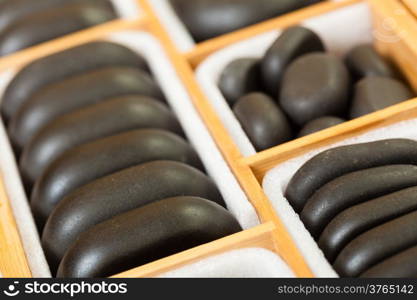 Beauty salon. Close up of black spa zen massage stones in wooden case as background. Relax concept.