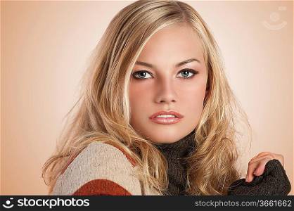 beauty shot of a gorgeous blonde girl with blue yes and natural make up wearing an autum color wool sweater