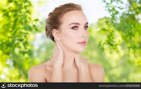 beauty, skin care and bodycare concept -beautiful young woman face and hands over green natural background. beautiful young woman face and hands