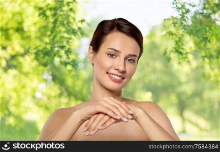 beauty, skin care and bodycare concept - beautiful young woman moisturizing her hands over green natural background. beautiful young woman moisturizing her hands skin