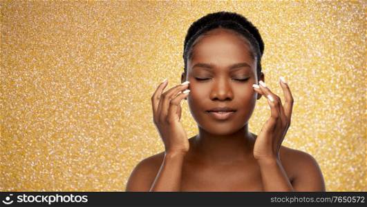 beauty, skin care and luxury concept - portrait of happy young african american woman with bare shoulders over golden glitter background. portrait of young african american woman