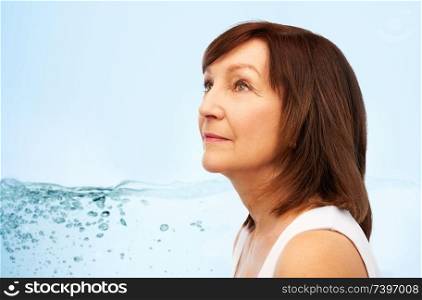 beauty, skin care and moisturizing concept - portrait of senior woman over blue background with bubbles in water splash. portrait of senior woman over blue water