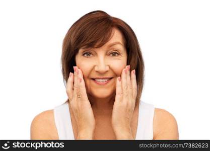beauty, skin care and old people concept - portrait of smiling senior woman touching her face over white background. portrait of smiling senior woman touching her face