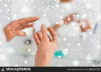 beauty, skin care and people concept - close up of happy young man with facial cream at bathroom over snow