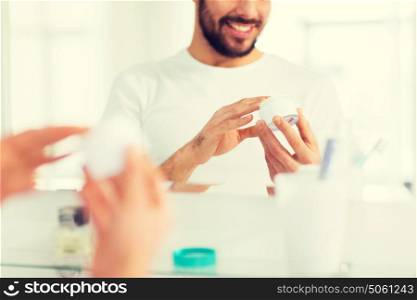 beauty, skin care and people concept - close up of happy young man with facial cream at bathroom. close up of happy young man with cream at bathroom