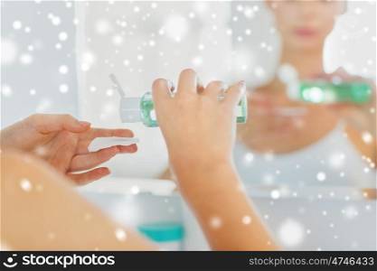 beauty, skin care and people concept - close up of young woman applying lotion to cotton disc for washing her face at bathroom over snow