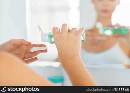 beauty, skin care and people concept - close up of young woman applying lotion to cotton disc for washing her face at bathroom