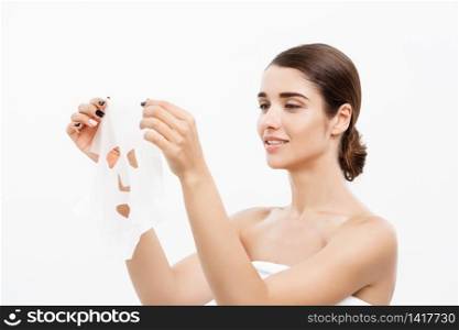 Beauty Skin Care Concept - Beautiful Caucasian Woman applying paper sheet mask on her face white background. Beauty Skin Care Concept - Beautiful Caucasian Woman applying paper sheet mask on her face white background.