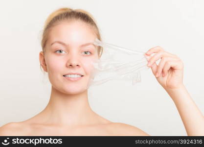 Beauty skin care cosmetics and health concept. Closeup young woman face, girl removing facial peel off mask on gray. Peeling