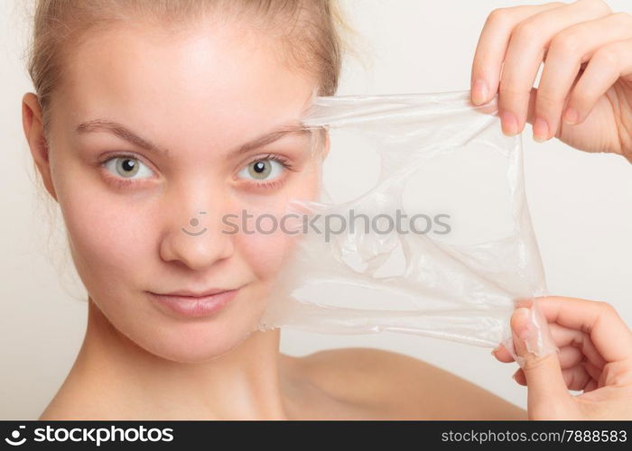 Beauty skin care cosmetics and health concept. Closeup young woman face, girl removing facial peel off mask on gray. Peeling