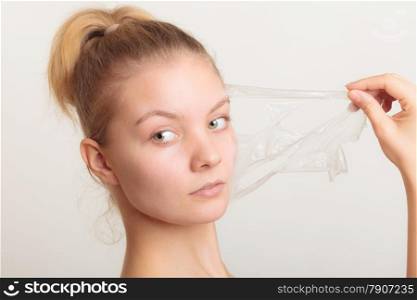 Beauty skin care cosmetics and health concept. Closeup young woman face, girl removing facial peel off mask on gray. Peeling