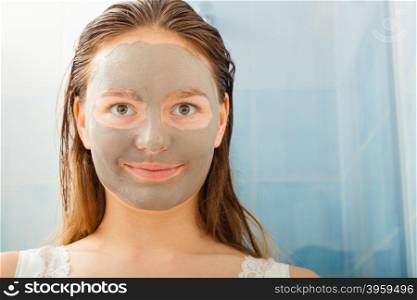 Beauty skin care cosmetics and health concept. Young woman face with facial clay mask in bathroom