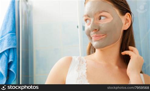 Beauty skin care cosmetics and health concept. Young woman face with facial clay mask in bathroom