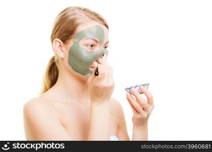 Beauty skin care cosmetics and health concept. Young woman holding brush and bowl with facial clay mask applying mud to her face isolated