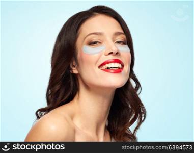 beauty, skin hydration and people concept - happy smiling young woman with hydrogel eye patches over blue background. beautiful young woman with hydrogel eye patches