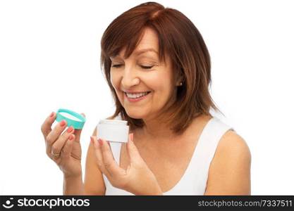 beauty, skincare and cosmetics concept - smiling senior woman with cream jar. smiling senior woman with cream jar