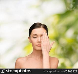 beauty, spa and health concept - calm young woman covering half of face with hand