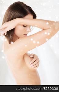 beauty, spa and people concept - beautiful naked woman covering breast over snowy background