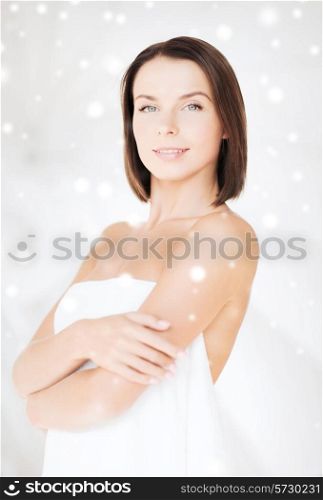 beauty, spa and people concept - beautiful woman standing in towel over snowy background