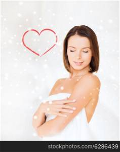 beauty, spa and people concept - beautiful woman standing in towel over snowy background