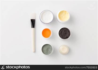 beauty, spa and wellness concept - blue clay mask, body butter and therapeutic mud with brush on white background. blue clay mask, body butter and therapeutic mud