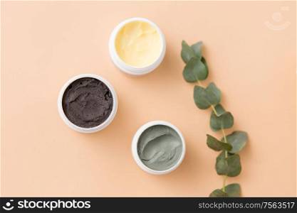 beauty, spa and wellness concept - blue clay mask, body butter, therapeutic mud and eucalyptus cinerea on beige background. blue clay mask, body butter and eucalyptus cinerea