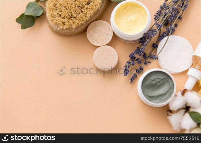 beauty, spa and wellness concept - close up of crafted soap bars, natural bristle wooden brush, body butter and herbs on beige background. soap, brush, sponge, clay mask and body butter