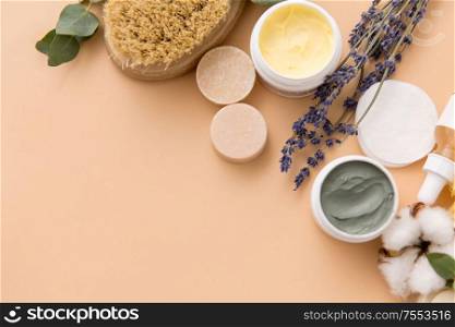 beauty, spa and wellness concept - close up of crafted soap bars, natural bristle wooden brush, body butter and herbs on beige background. soap, brush, sponge, clay mask and body butter