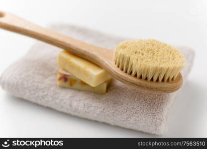 beauty, spa and wellness concept - close up of crafted soap bars and natural bristle wooden brush on bath towel. crafted soap bars, natural brush and bath towel