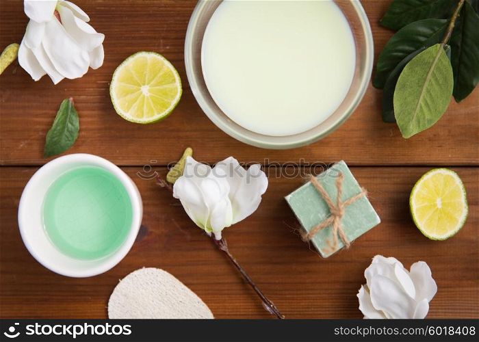 beauty, spa, body care and natural cosmetics concept - close up of bowls with citrus body lotion, cream and soap on wooden table
