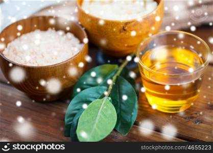 beauty, spa, body care and natural cosmetics concept - honey in glass with himalayan pink salt and leaves on wooden table over snow