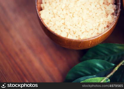 beauty, spa, body care, bath and natural cosmetics concept - close up of himalayan pink salt in wooden bowl with leaves. close up of himalayan pink salt in wooden bowl