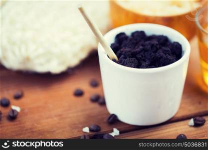 beauty, spa, body care, bath and natural cosmetics concept - close up of coffee scrub in cup on wooden table. close up of coffee scrub in cup on wooden table